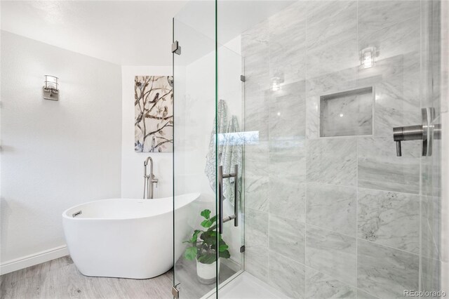 bathroom with baseboards, a freestanding tub, and a shower stall