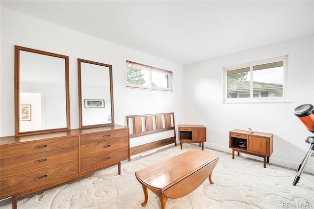 living area featuring baseboards, a healthy amount of sunlight, and light colored carpet