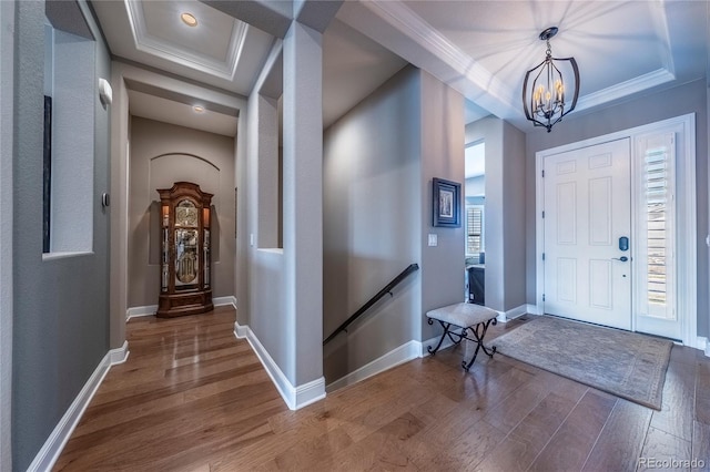 foyer entrance featuring crown molding, a chandelier, and wood finished floors