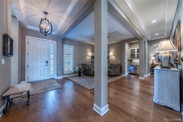 entrance foyer featuring baseboards, dark wood finished floors, a chandelier, and a tray ceiling