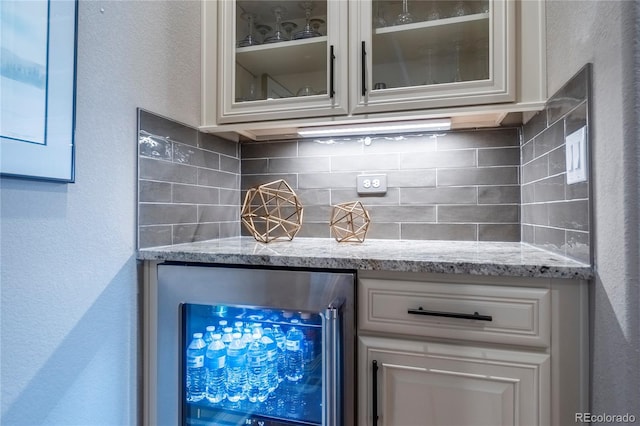 bar with wine cooler, decorative backsplash, and a textured wall