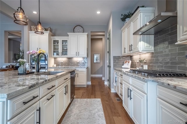 kitchen featuring white cabinets, appliances with stainless steel finishes, a sink, and wall chimney exhaust hood