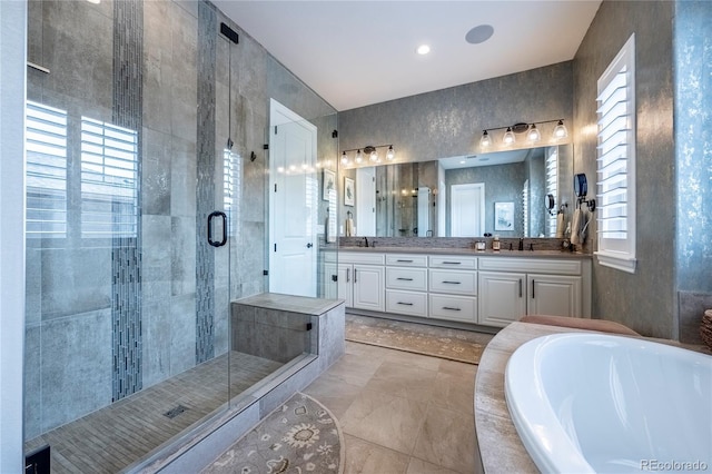 bathroom with double vanity, a shower stall, a sink, and a garden tub