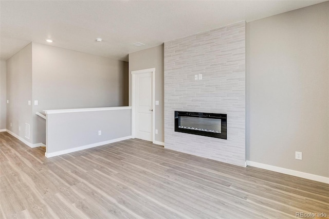 unfurnished living room with a fireplace and light hardwood / wood-style floors