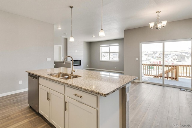 kitchen with white cabinetry, dishwasher, sink, hanging light fixtures, and a kitchen island with sink