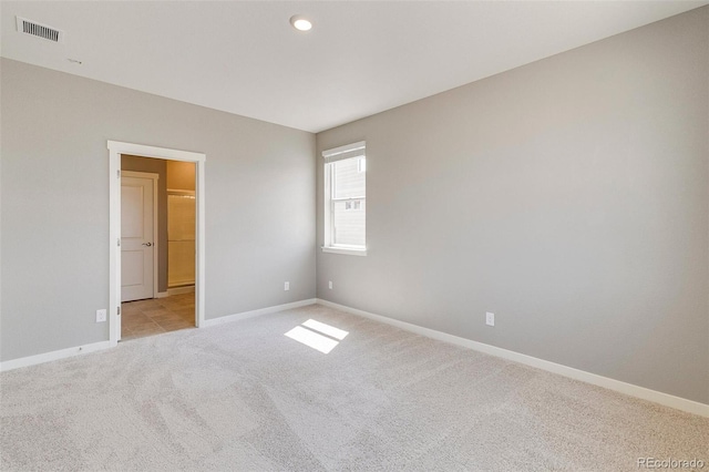 unfurnished bedroom with light colored carpet and ensuite bathroom