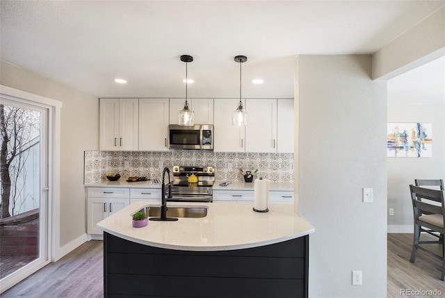 kitchen featuring stainless steel appliances, a sink, white cabinetry, decorative backsplash, and recessed lighting