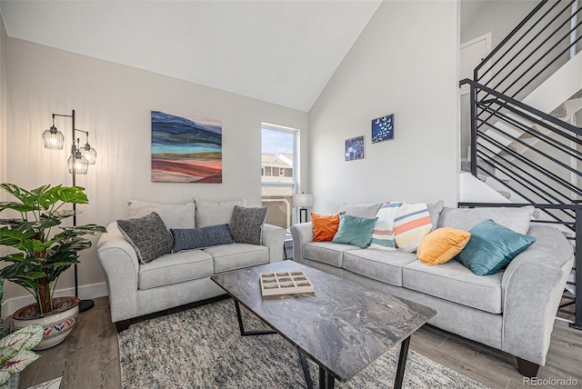 living room featuring wood finished floors, stairs, high vaulted ceiling, and baseboards