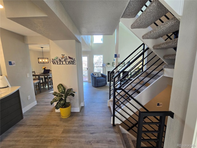 entryway with wood finished floors, stairway, baseboards, and a chandelier