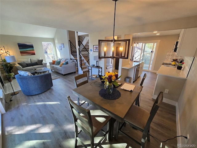 dining area with stairs, dark wood finished floors, a chandelier, and baseboards