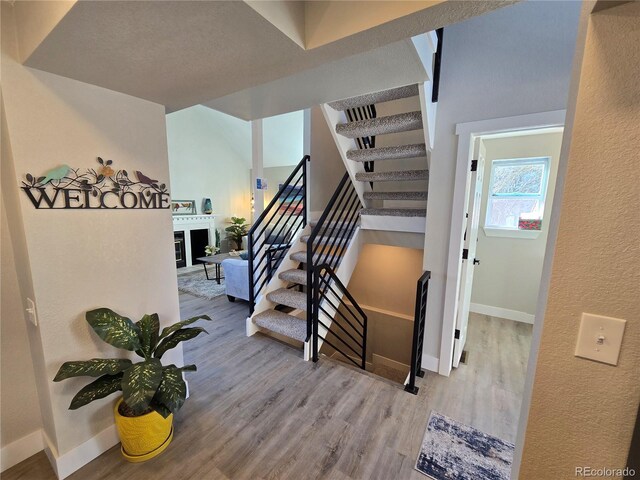 stairs with wood finished floors, baseboards, and a textured wall