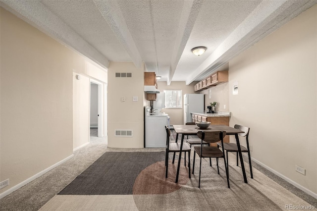 dining space featuring carpet flooring, washing machine and dryer, and a textured ceiling