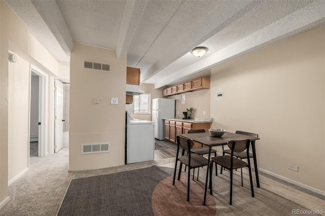 carpeted dining space featuring washer / clothes dryer and a textured ceiling