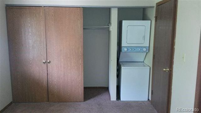 laundry area with light carpet and stacked washer and clothes dryer