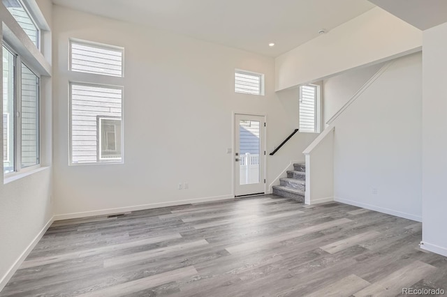 foyer entrance with a towering ceiling, light hardwood / wood-style floors, and a wealth of natural light