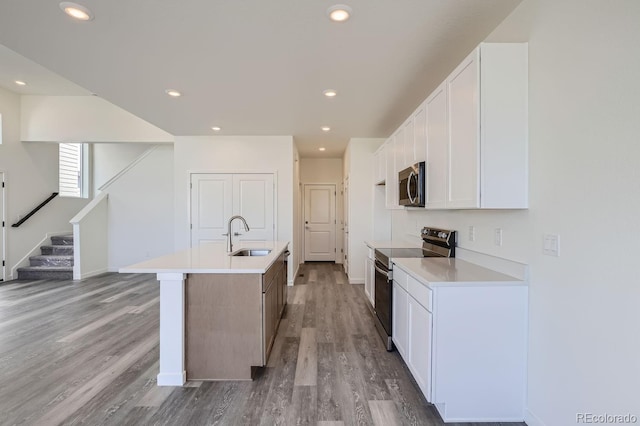 kitchen featuring light hardwood / wood-style floors, sink, stainless steel appliances, an island with sink, and white cabinets