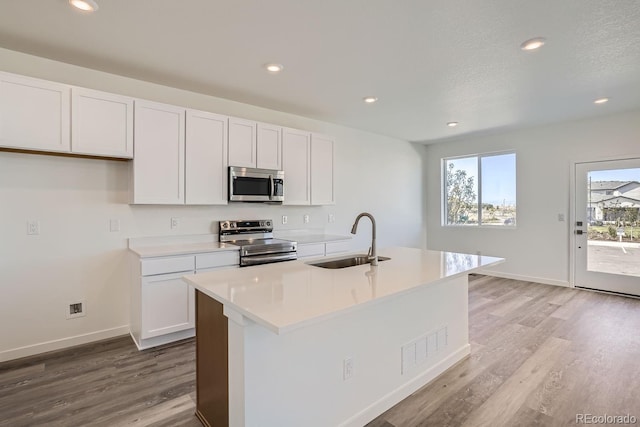 kitchen featuring white cabinets, a center island with sink, appliances with stainless steel finishes, and sink