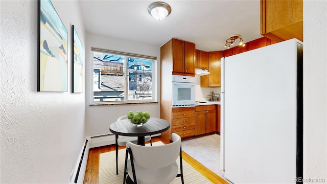 kitchen with baseboard heating and white appliances