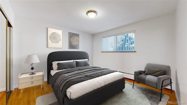 bedroom featuring wood-type flooring, a closet, and a baseboard heating unit