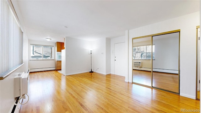 spare room with a baseboard heating unit and light hardwood / wood-style floors