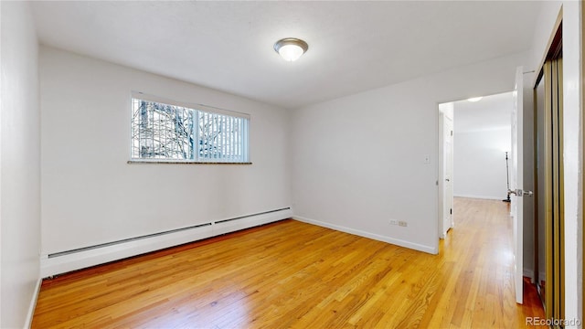 empty room featuring a baseboard radiator and light wood-type flooring