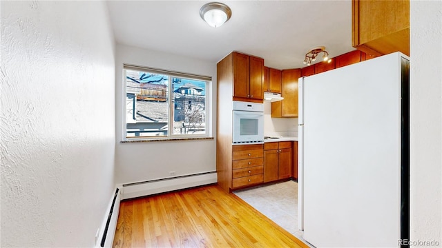 kitchen featuring white appliances, a baseboard radiator, and light hardwood / wood-style floors