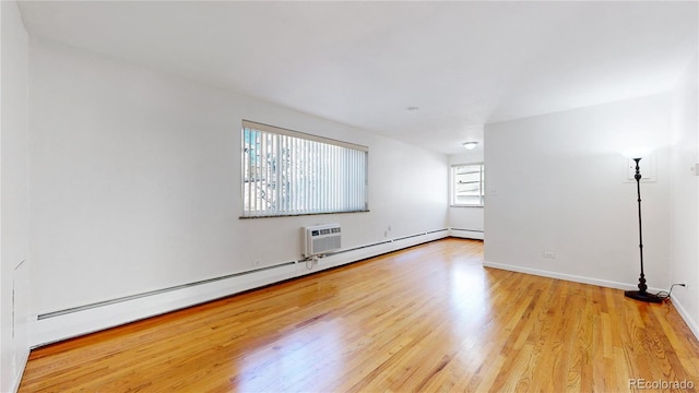 unfurnished room with a wall mounted air conditioner, a baseboard radiator, and light wood-type flooring