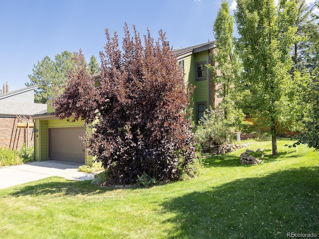 view of property hidden behind natural elements featuring a front yard and a garage