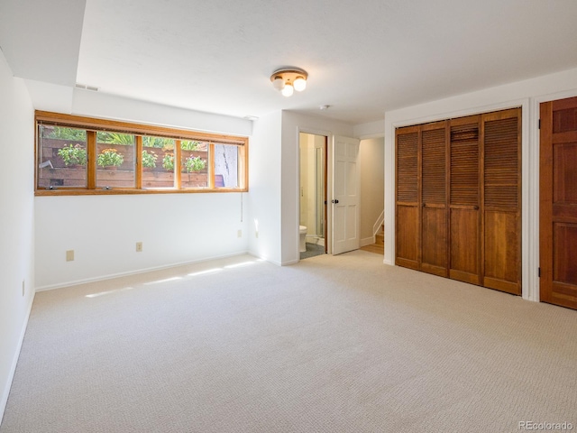 unfurnished bedroom featuring multiple closets and light colored carpet