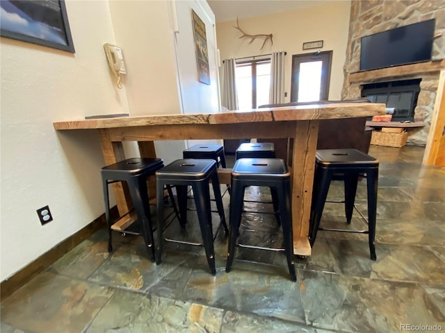 bar featuring stone finish floor, a fireplace, and baseboards