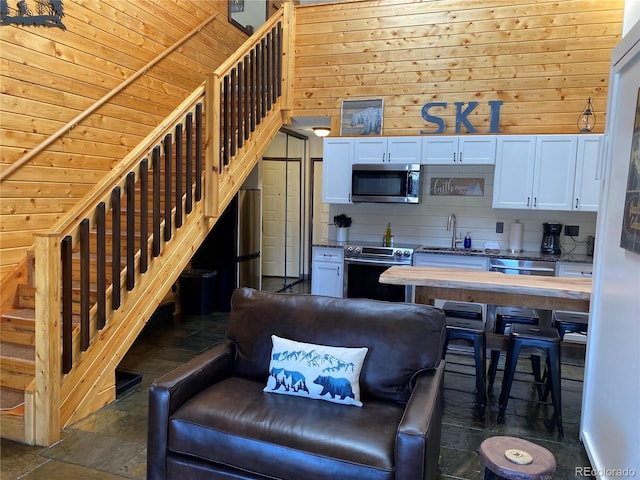 living room featuring stairway, stone finish floor, and wooden walls