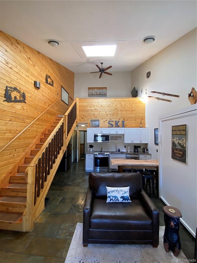 interior space with a ceiling fan, stone finish flooring, and wood walls