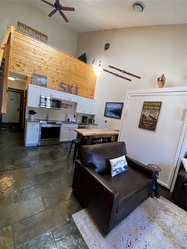 kitchen featuring high vaulted ceiling, white cabinetry, appliances with stainless steel finishes, and ceiling fan