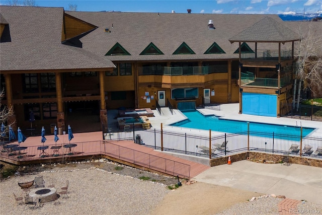 community pool with a fire pit, a patio, and fence