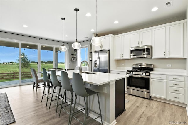 6513 Dry Fork Cir, Frederick, CO 80516 - kitchen with stainless steel appliances, a center island with sink, white cabinetry, a breakfast bar, and recessed lighting