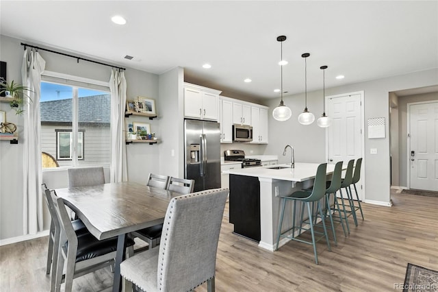6513 Dry Fork Cir, Frederick, CO 80516 - kitchen with stainless steel appliances, a kitchen island with sink, light wood finished floors, recessed lighting, and white cabinets