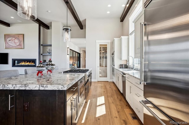 kitchen with light hardwood / wood-style floors, white cabinetry, hanging light fixtures, a kitchen island, and appliances with stainless steel finishes