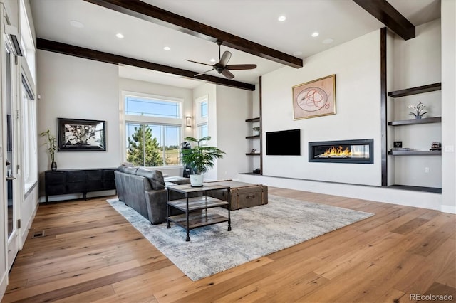 living room featuring light hardwood / wood-style flooring, ceiling fan, and beamed ceiling