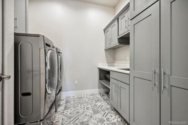 washroom with light tile patterned floors, washer and dryer, and cabinets