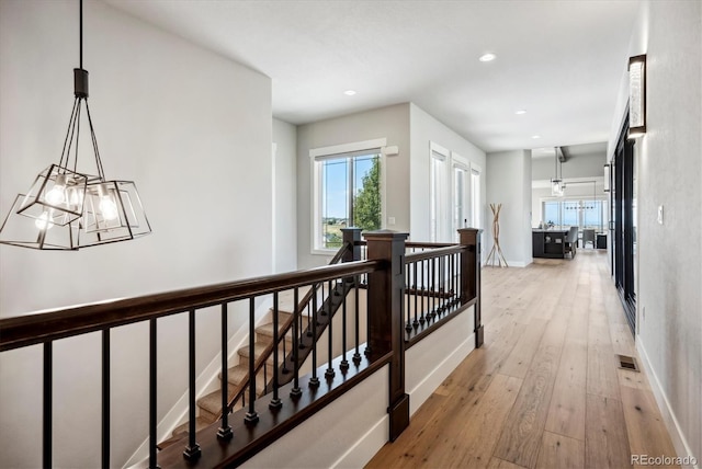 hall with light hardwood / wood-style flooring and an inviting chandelier