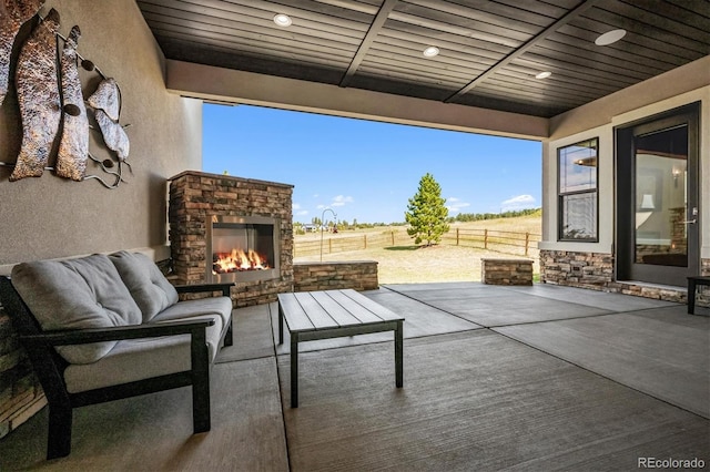 view of patio with an outdoor stone fireplace and a rural view