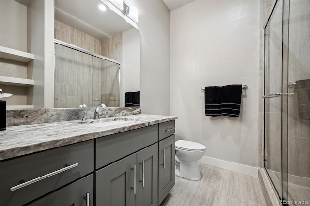 bathroom with hardwood / wood-style floors, an enclosed shower, vanity, and toilet