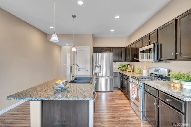 861 Circle Rd, Palmer Lake, CO 80133 - kitchen with dark brown cabinets, light wood-style floors, light stone counters, a sink, and stainless steel appliances