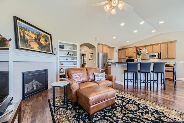 living room featuring lofted ceiling, ceiling fan, dark hardwood / wood-style floors, and built in shelves