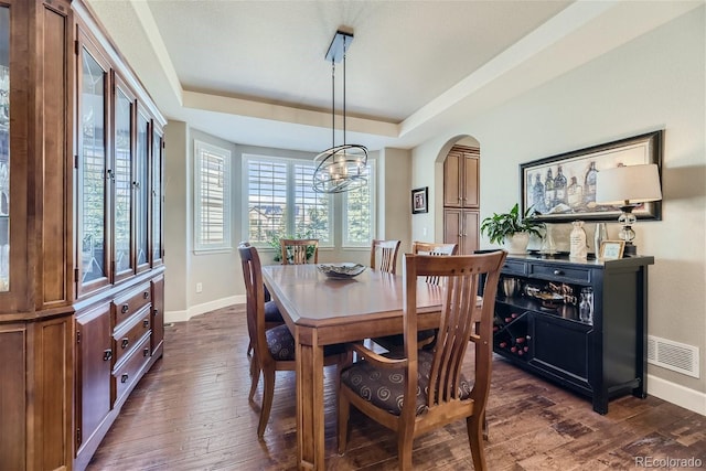 dining area featuring dark hardwood / wood-style floors, a notable chandelier, and a tray ceiling