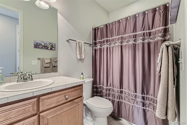 bathroom with tile floors, vanity, and toilet