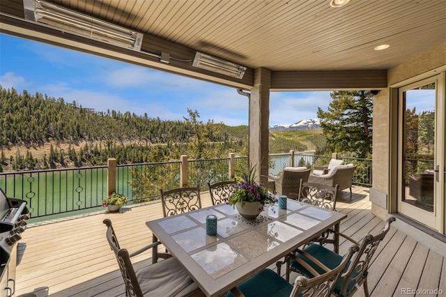 309 Eastridge Dr, Dillon, CO 80435 - wooden deck featuring outdoor dining area, a mountain view, and a view of trees