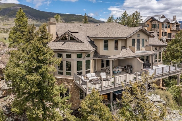 309 Eastridge Dr, Dillon, CO 80435 - back of property with a balcony, an outdoor living space, a chimney, stucco siding, and stone siding