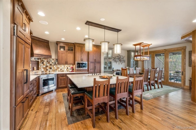 309 Eastridge Dr, Dillon, CO 80435 - kitchen featuring stainless steel range oven, wall chimney exhaust hood, brown cabinets, light countertops, and light wood-type flooring