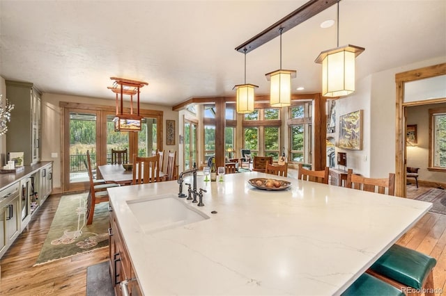 309 Eastridge Dr, Dillon, CO 80435 - kitchen with light wood-style floors, a kitchen bar, french doors, light stone countertops, and decorative light fixtures